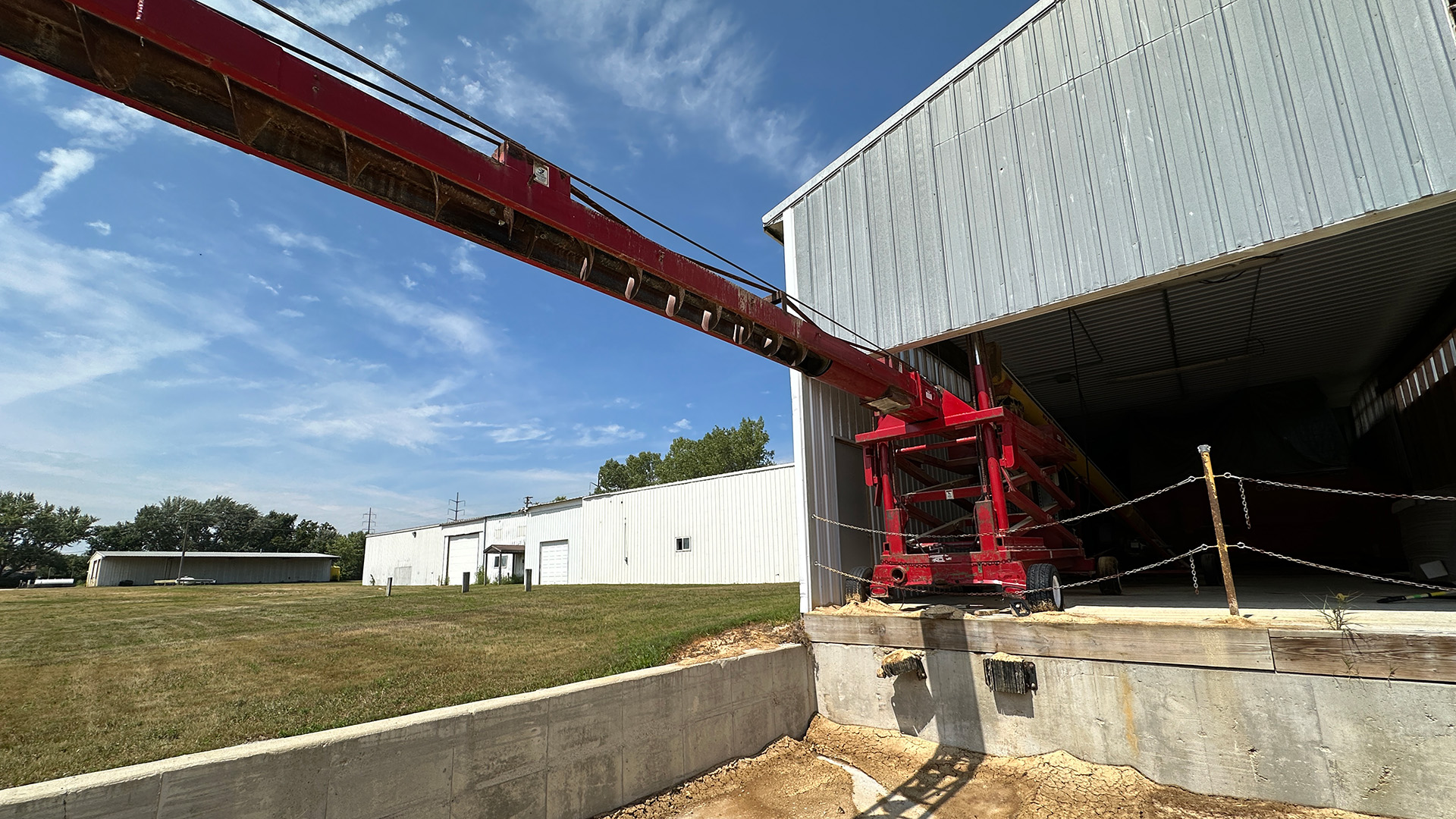 Machinery at a food production plant next to a white industrial building 