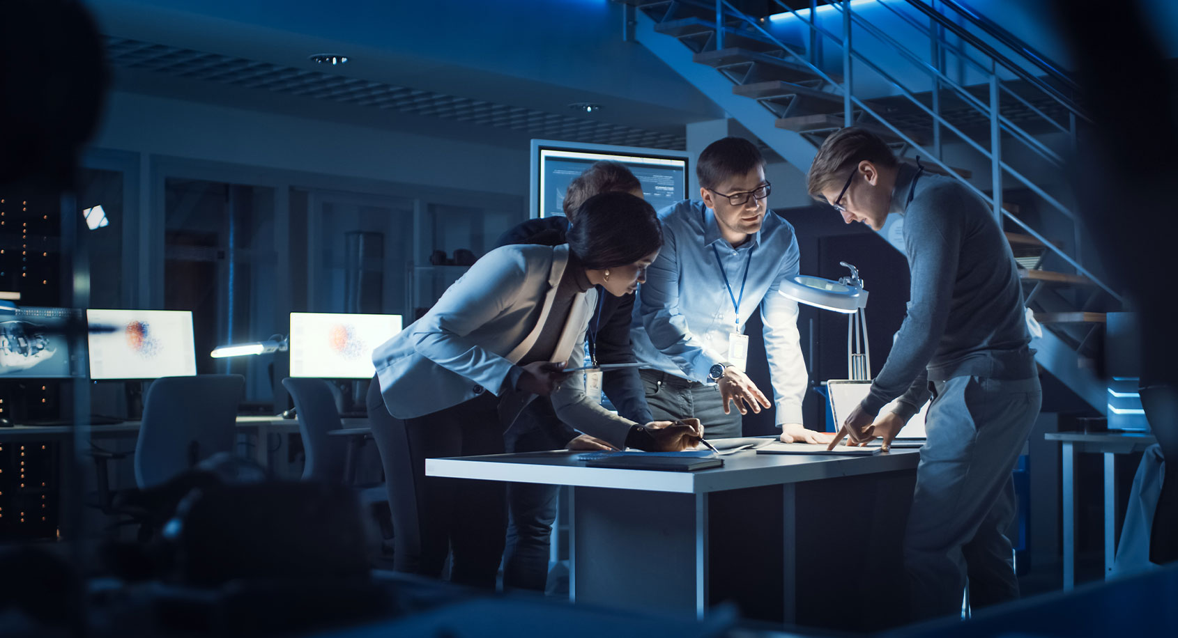People standing around a desk in the dark