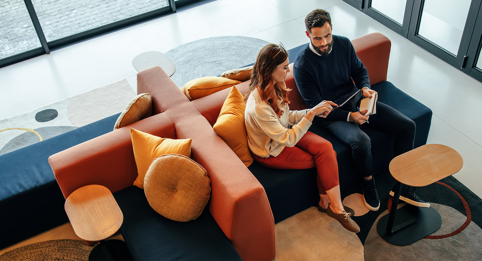 Man and woman sitting in modern orange office furniture